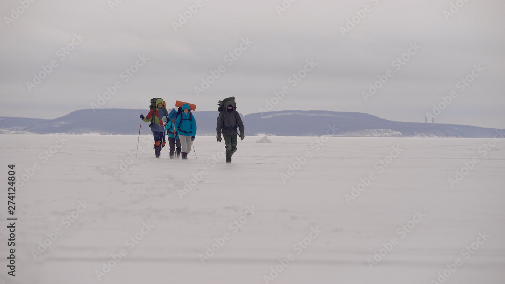 Four young people go hiking in the snowy desert.