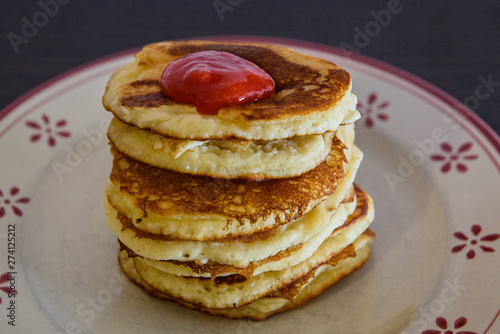 Stack of Homemade pancakes with freshly blended strawberries on plate.