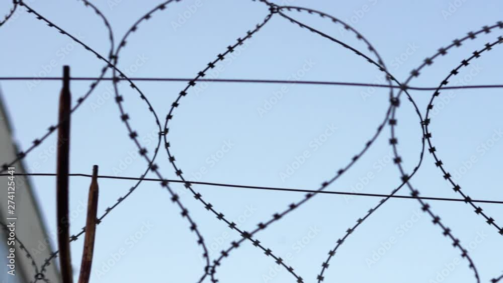 A fence with barbed wire against the sky. Close-up. Security systems Restricted area. Restriction of human freedom A fence with barbed wire against the sky. Close-up. Security systems Restricted area. Restriction of human freedom