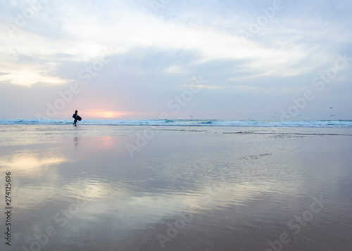 passear e surfar em praia vazia ao por do sol