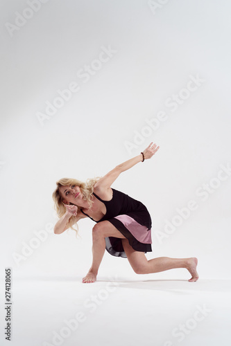 Image of long-haired blonde looking to side with outstretched hand dancing in studio
