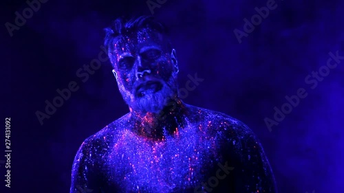 Concept. Portrait of a bearded man. The man is painted in ultraviolet powder photo