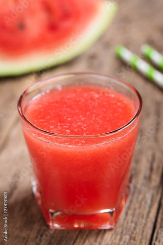 Refreshing watermelon juice on rustic wood (Selective Focus, Focus on the front of the glass rim)