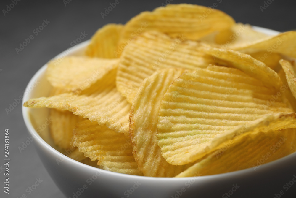 Tasty potato chips in bowl, closeup view