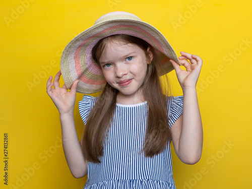 Summer portrait of a beautiful little cute girl in a hat and dress, the concept of a summer holiday, childhood, children's fashion