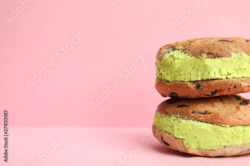 Sweet delicious ice cream cookie sandwiches on color background, space for text