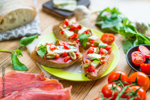 Traditional Italian bruschetta with blue cheese  feta  tomatoes  basil leaves  jamon on a wooden background.