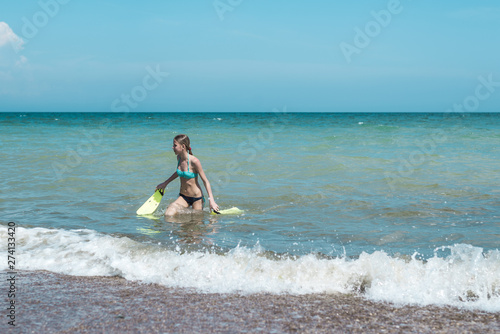 Teen girl with flippers in hands on the sea, ocean. Summer outdoor activities during the holidays. © Konstiantyn Zapylaie