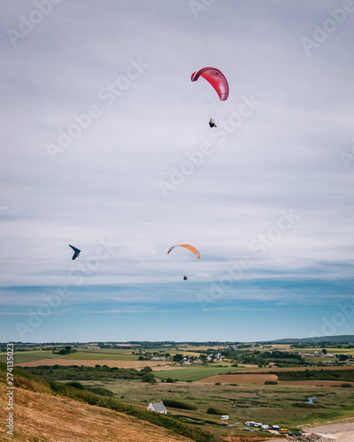 A hang glider and two paragliders over the beach of Kervijen in Brittany, France