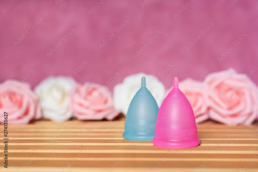 Menstrual cups from a medicinal silicone. Pink and white roses. Concept of alternative solution - zero waste intimate hygiene for women. Menstrual cups from a medicinal silicone. Pink and white roses. Concept of alternative solution - zero waste intimate hygiene for women.