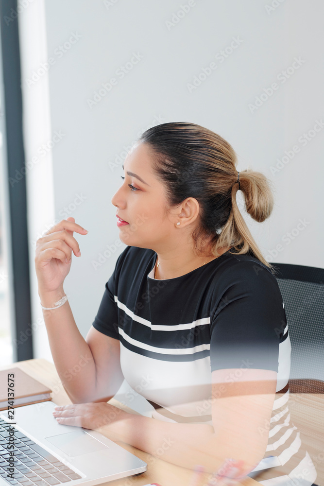 Obraz premium Young Asian female executive sitting at her workplace with laptop computer at office