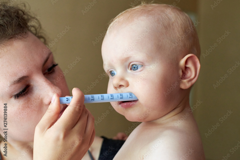 Mom gives her child medicine through a syringe Mom gives her child medicine through a syringe
