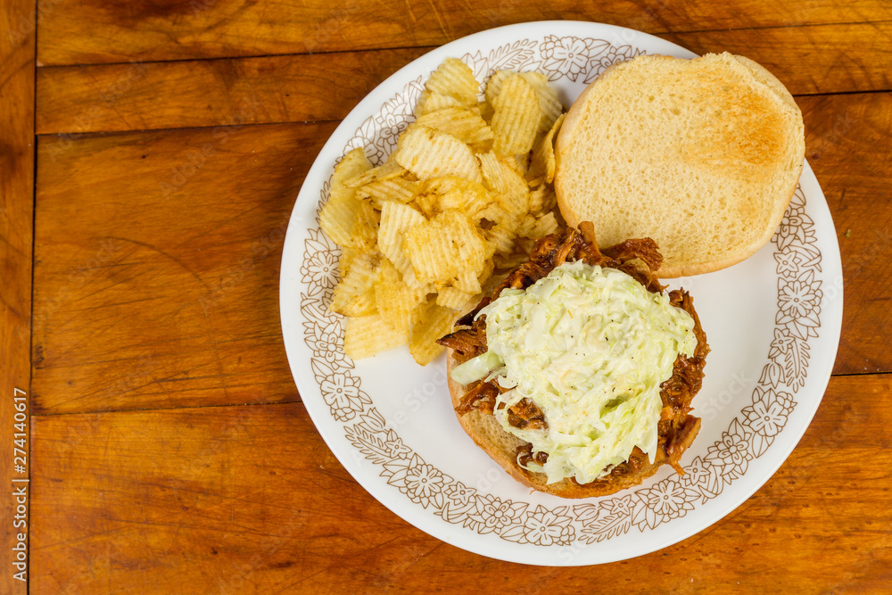 Pulled Pork BBQ Sandwich topped with Coleslaw and Served with Potato Chips Pulled Pork BBQ Sandwich topped with Coleslaw and Served with Potato Chips