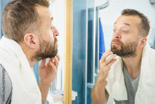 Man looking at his beard in mirror