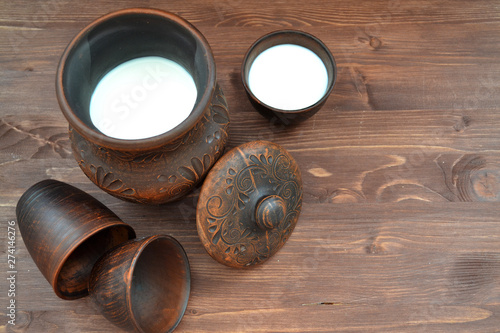 Milk in rustic pottery on dark background. Flat view with copy space