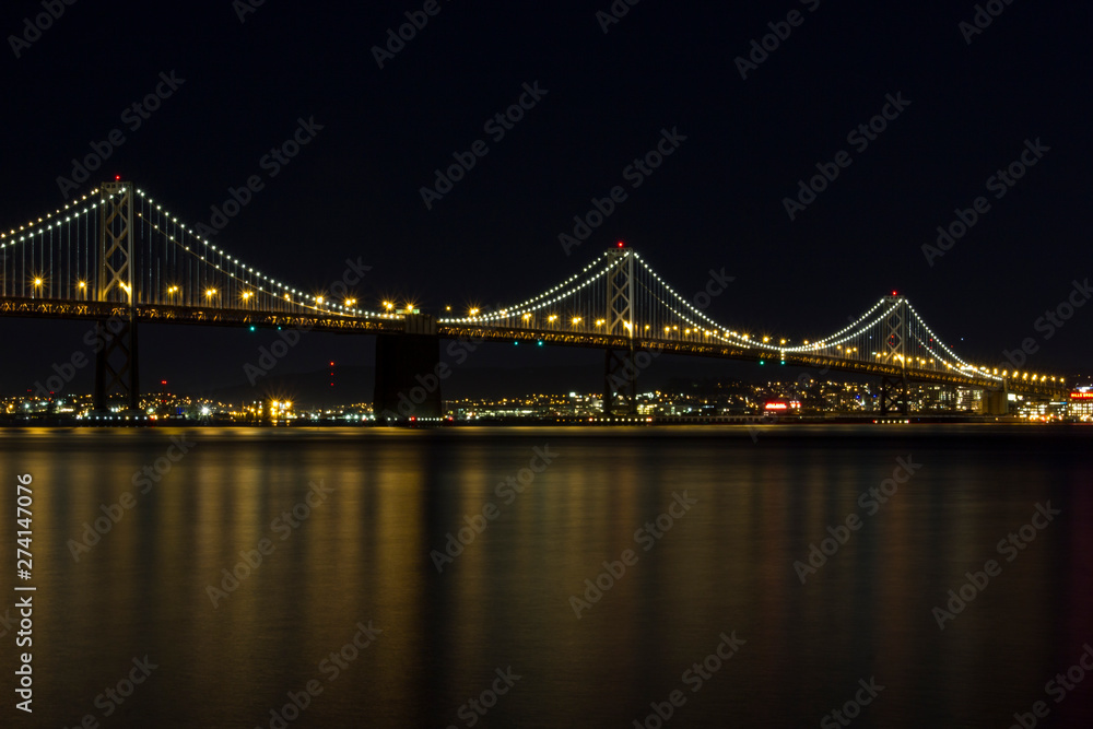 Bay Bridge reflecting on the ocean at night in San Francisco California