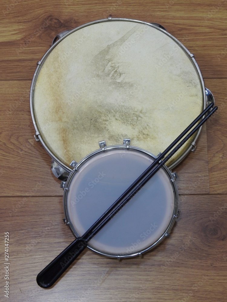 Fototapeta premium Close-up of two Brazilian percussion musical instruments: pandeiro (tambourine) and tamborim with drumstick on a wooden surface. These instruments are widely used to accompany samba music.