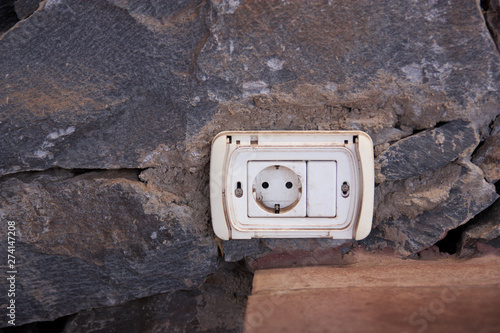 An aged plug placed on a rustic stone wall