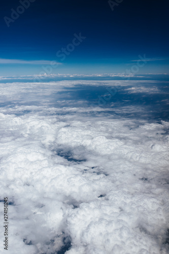 Plane window view with blue sky and beautiful clouds. As seen through window of an aircraft. View of wing & ocean. Airplane from city Bangkok to island Bali.