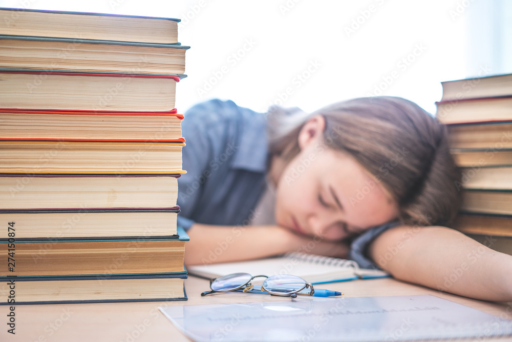 Stressed college student tired of hard learning with books in exams tests preparation, overwhelmed high school teen girl exhausted with difficult studies or too much homework, cram concept Stressed college student tired of hard learning with books in exams tests preparation, overwhelmed high school teen girl exhausted with difficult studies or too much homework, cram concept