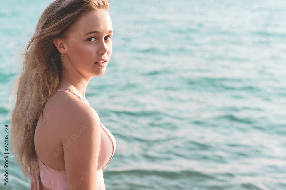 young slim beautiful woman in pink bikini on tropical beach. Portrait of happy young woman smiling at sea. Girl in swimwear enjoying and walking on beach. young slim beautiful woman in pink bikini on tropical beach. Portrait of happy young woman smiling at sea. Girl in swimwear enjoying and walking on beach.