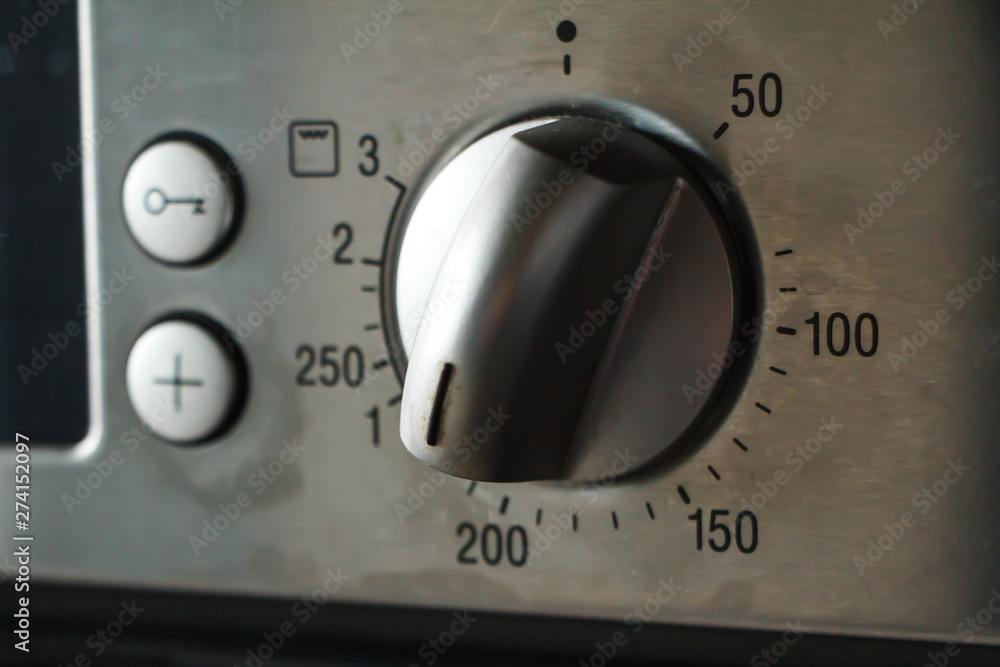 A close-up of a metal temperature and mode switch on the oven indicates a temperature of 180 degrees, selective focus A close-up of a metal temperature and mode switch on the oven indicates a temperature of 180 degrees, selective focus