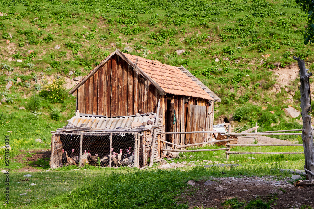 Old decrepit farmhouse surrounded by mountains and a mountain river with a blue sky. It is located in the mountains of Tien Shan. Old decrepit farmhouse surrounded by mountains and a mountain river with a blue sky. It is located in the mountains of Tien Shan.