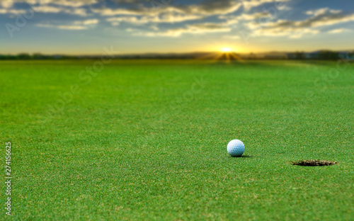White Golf ball on green course to be shot on blurred beautiful landscape of golf course in bright day time with copy space. Sport, Recreation, Relax in holiday concept 