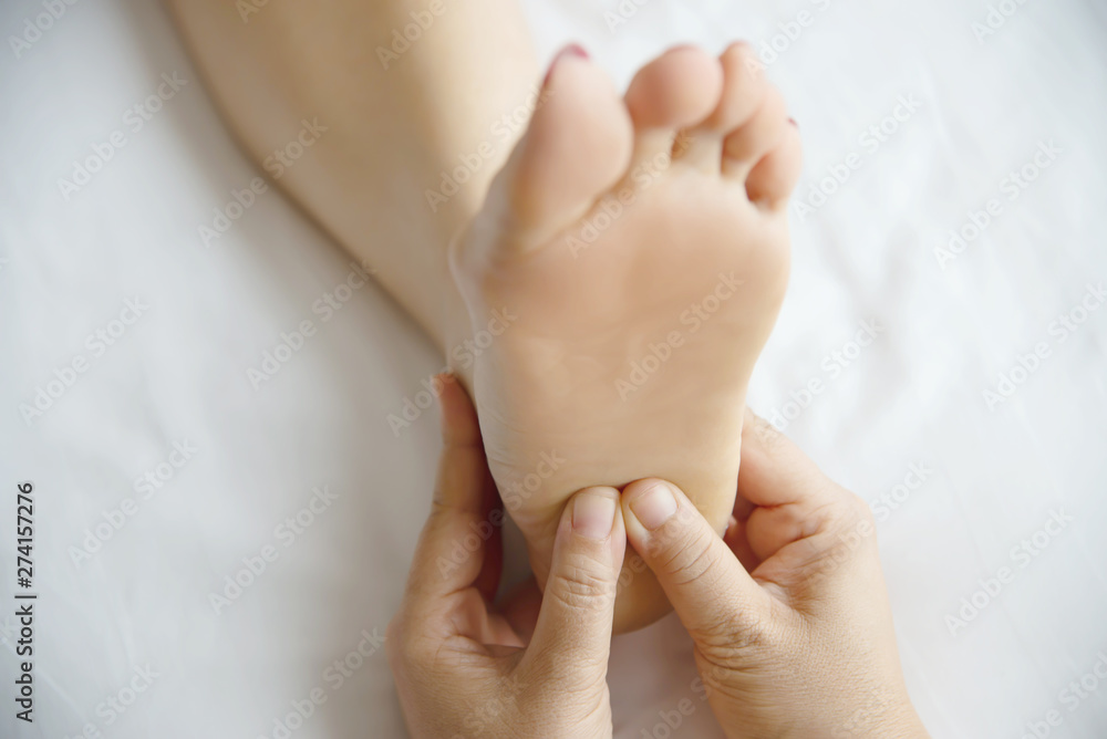 Woman receiving foot massage service from masseuse close up at hand and foot - relax in foot massage therapy service concept Woman receiving foot massage service from masseuse close up at hand and foot - relax in foot massage therapy service concept