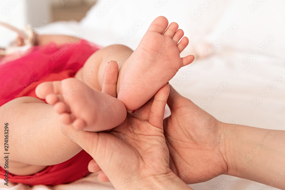 mother hands holding baby feet on the white bed mother hands holding baby feet on the white bed