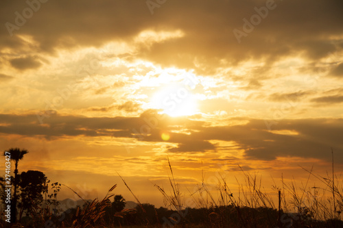 Evening weather  Golden sky and cloud with Light sunshine  Dark shadow meadow in the field and far away as a mountain.