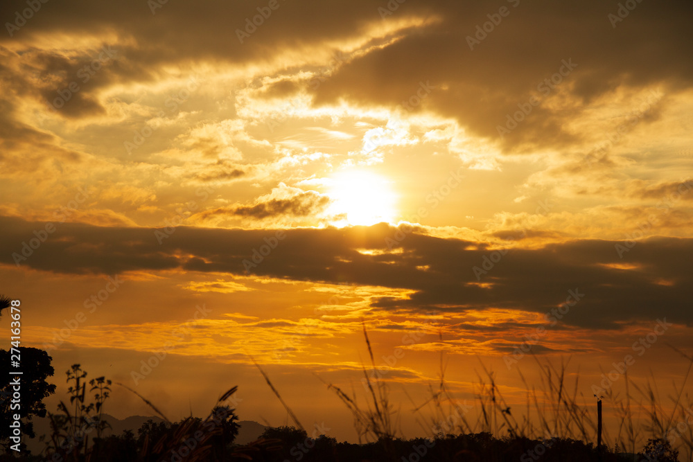 Evening weather, Golden sky and cloud with Light sunshine, Dark shadow meadow in the field and far away as a mountain.