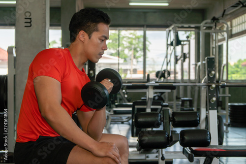 male having exercise lifting dumbbell in gym