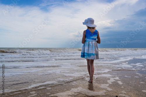 Seascape. A girl in a beautiful dress and a white hat on the beach
