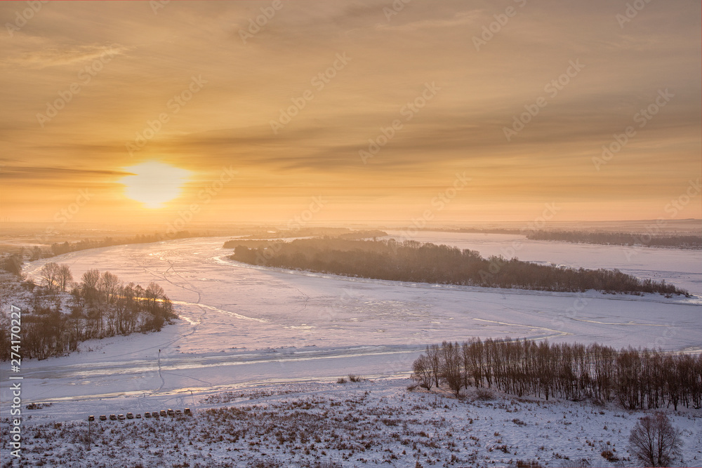 Panoramic view on frozen river and forest on hill in winter during sunset from hill Panoramic view on frozen river and forest on hill in winter during sunset from hill
