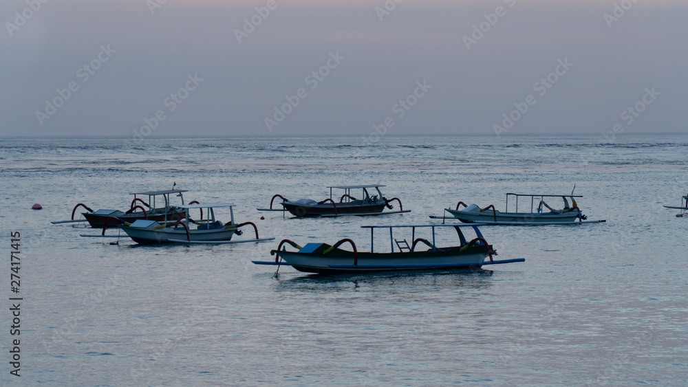 Nusa Penida, Indonesia- June 7,2019 : Wooden boats during sunset at Crystal Bay Beach in Nusa Penida, Indonesia