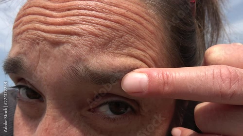 4K Close up Woman touches a pustule on her eyebrow with her fingers