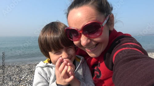 4K Selfie mother and child pose against the Mediterranean sea and rub noses photo