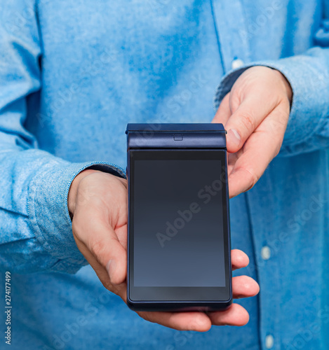 The man is holding a modern blue terminal for payment.