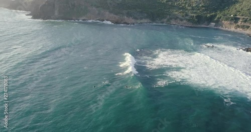 OUTDOORS 4K Aerial shot of a small group of surfers sitting on surfboards waiting for waves, cold water mediterranean sea