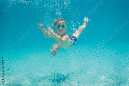 Boy having fun playing underwater in swimming pool on summer vacation