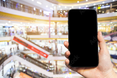 Close-up of female use Hand holding smartphone blurred images touch of Abstract blur of inside shopping complex background,shopping online concept.