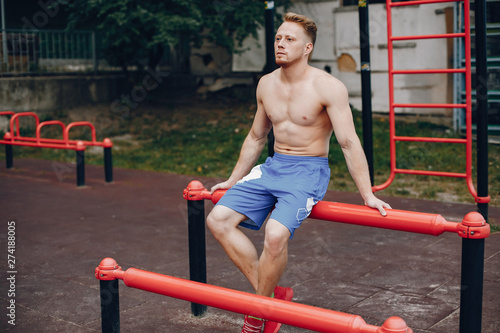 Man training. Guy in a sports shorts. Male in a summer park