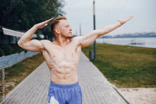 Man training. Guy in a sports shorts. Male in a summer park