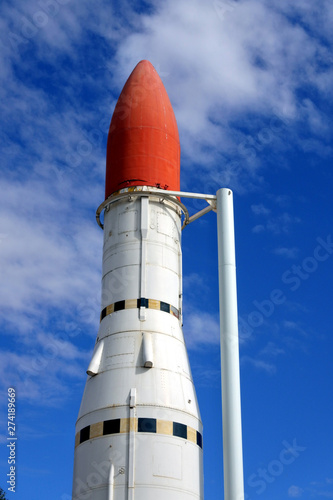 Space rocket against blue sky with clouds