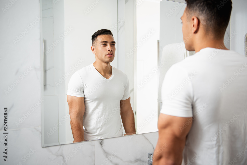 Fototapeta premium Back side portrait of young man looking at mirror