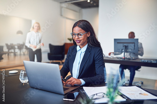 Smiling African American businesswoman sitting at work using a l