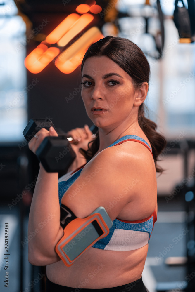 Fototapeta premium Dark-haired woman with overweight working out in gym