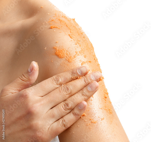 Beautiful young woman applying body scrub against white background, closeup