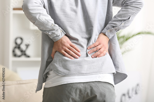 Young man suffering from back pain at home